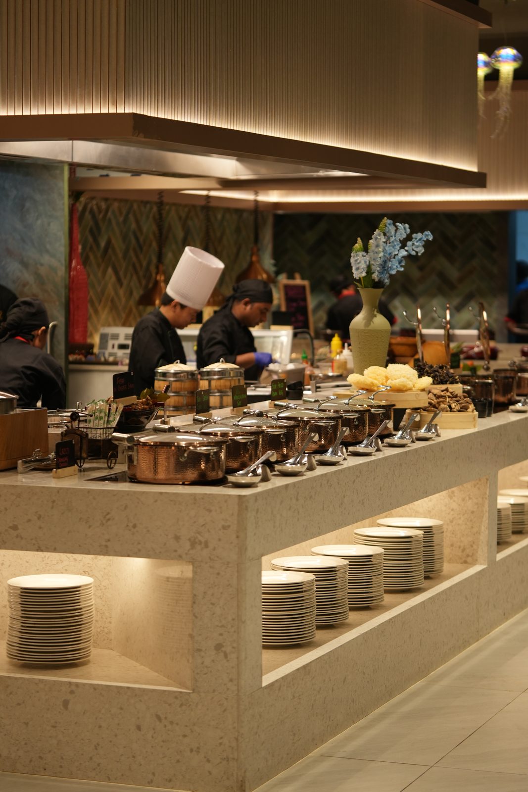Chefs at the open live kitchen behind a marble buffet counter