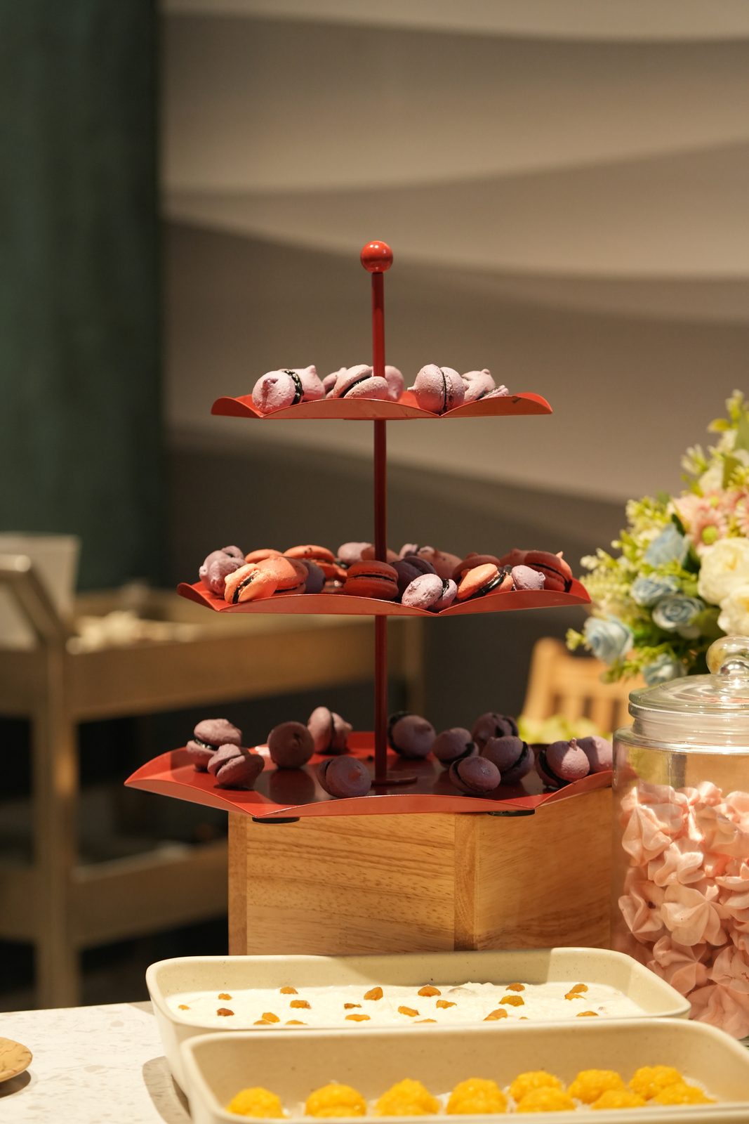 A tiered stand of macarons beside jars of sweets