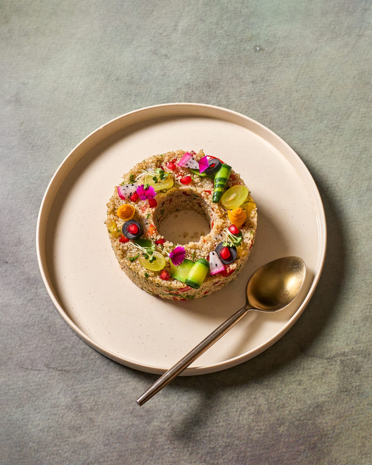 A ring of rice topped with colourful vegetables on a cream plate